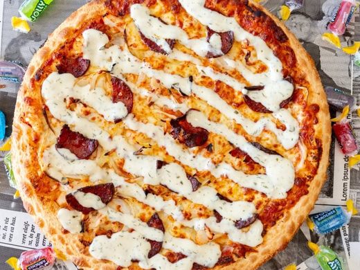 Jolly Rancher pizza drizzled with ranch sauce, surrounded by Jolly Rancher lollies